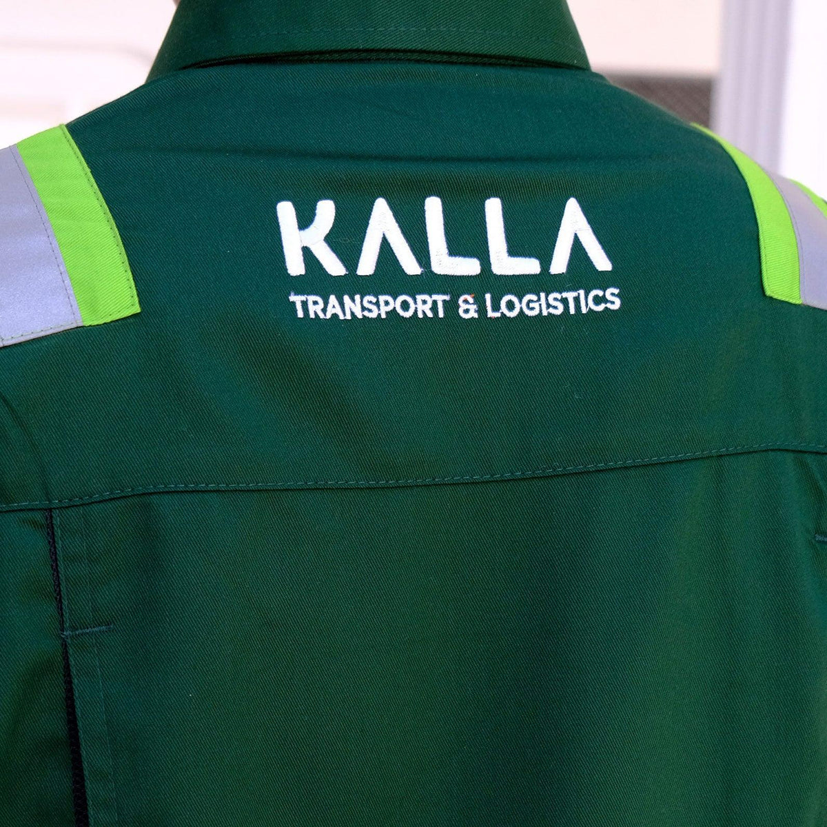 Back view of a green work uniform with KALLA Transport & Logistics white embroidery