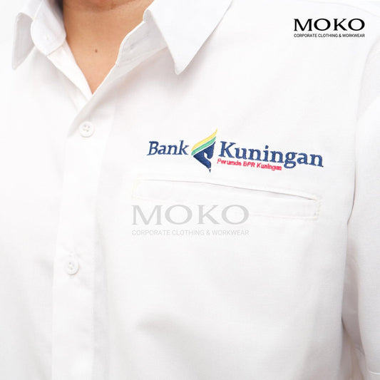 Close-up of a white corporate shirt with Bank Kuningan logo embroidery on the chest.